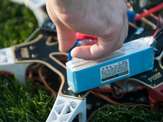 A close up of a person's hand holding a wire connected to a drone.