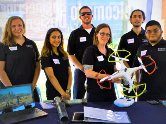 A group of students posing for a photo with a drone.