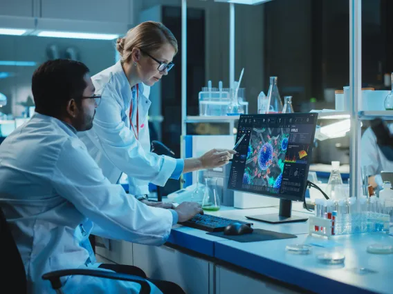 Two engineers looking at biological models on a computer screen.